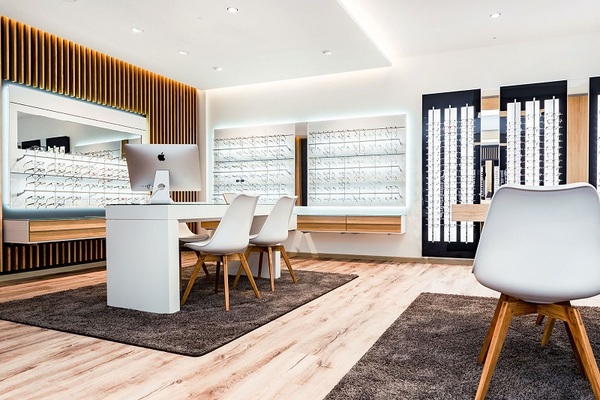 Modernes Optiker-Geschäft mit Brillenauswahl, Beratungstisch und stilvoller Einrichtung.